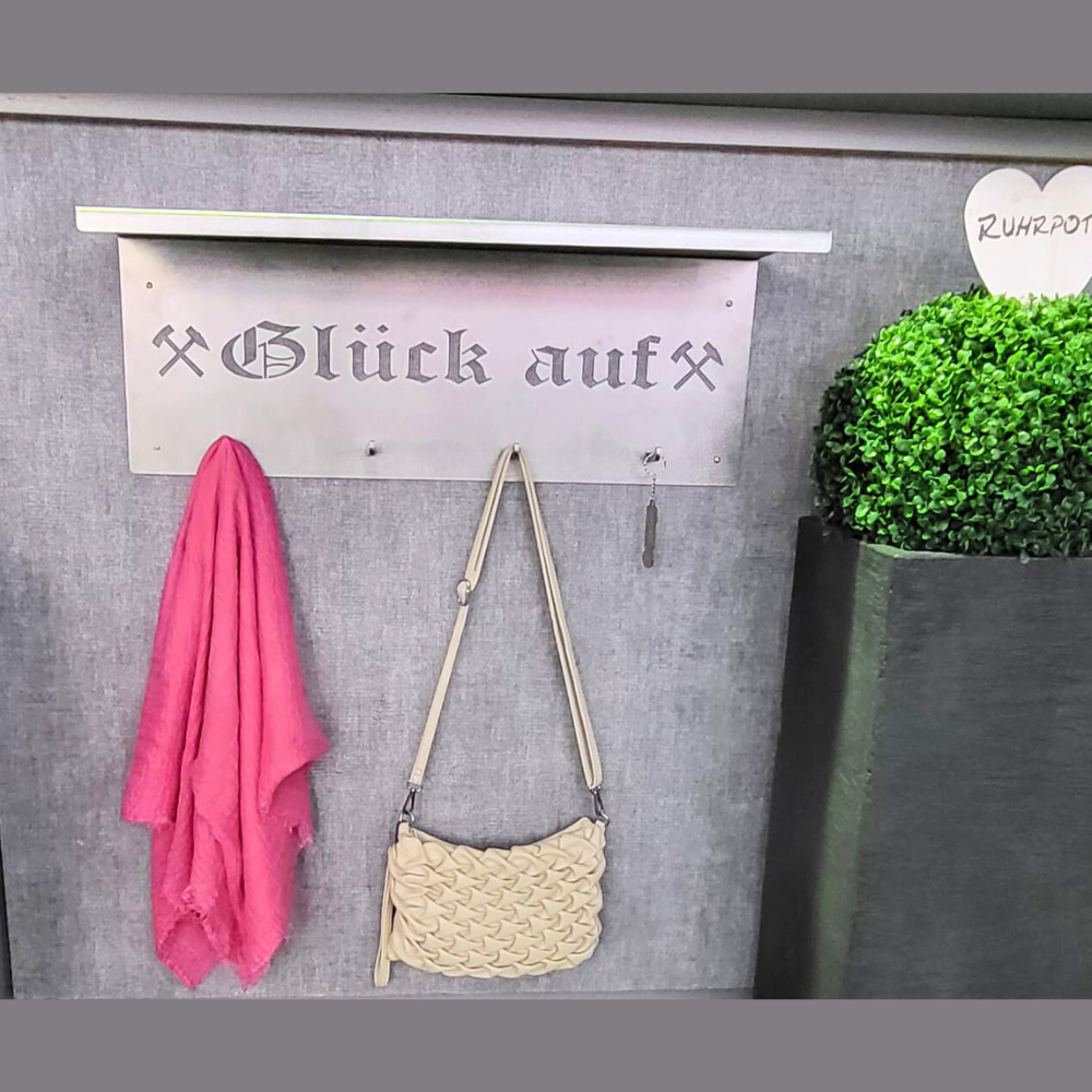 Garderobe aus Stahl mit dem Schriftzug Glück auf und den Eisen und Schlägel Symbolen. Zum Aufhängen an die Wand.