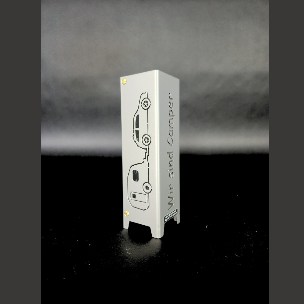 Windflicht aus Metall mit einem Motiv Wohnwagen und Auto sowie den Schriftzug auf der anderen Seite: WIR SIND CAMPER. Das Windlicht aus Metall ist vierseitig gelasert, jeweils zweimal Motiv Wohnwagen mit Auto gegenüberliegend und den Schriftzug: WIR SIND