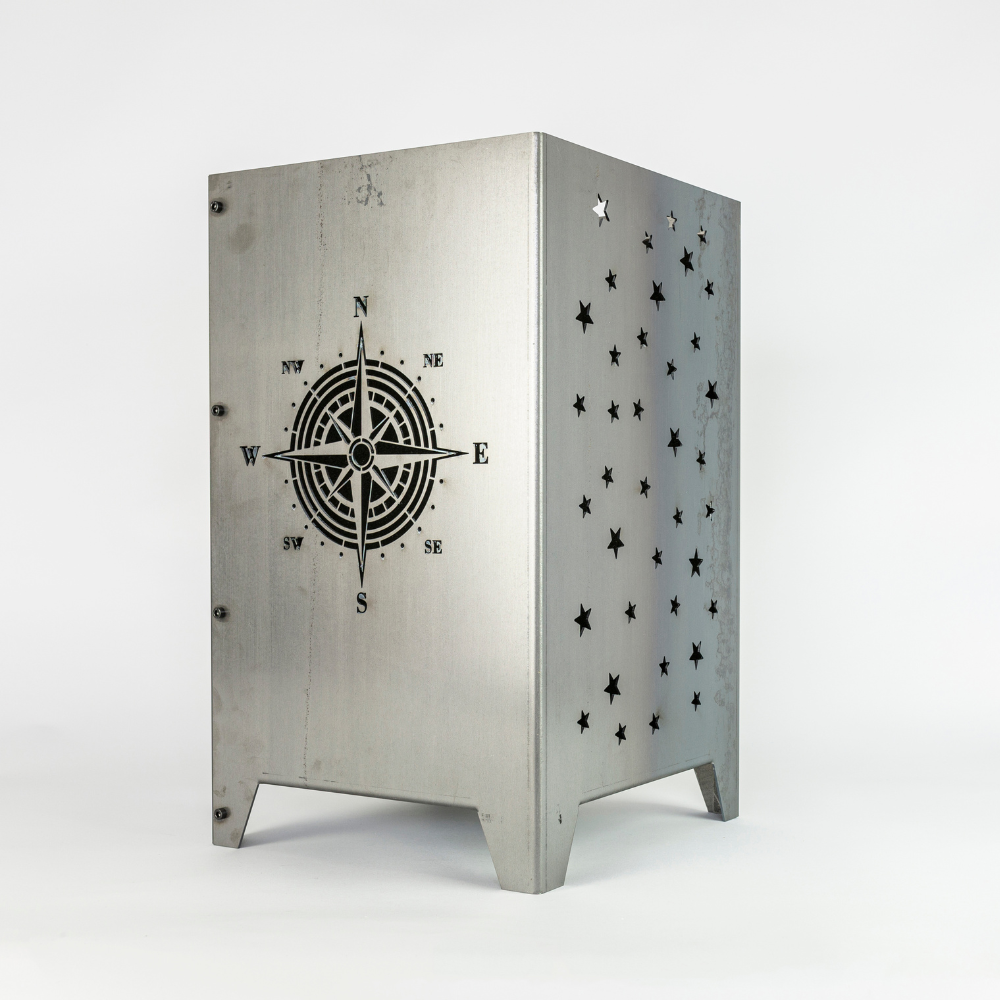 Feuersäule mit dem Motiv Kompass auf der einen Seite eingelasert. Auf der anderen Seite der Feuersäule sind Sterne. Aus Stahl gefertigt