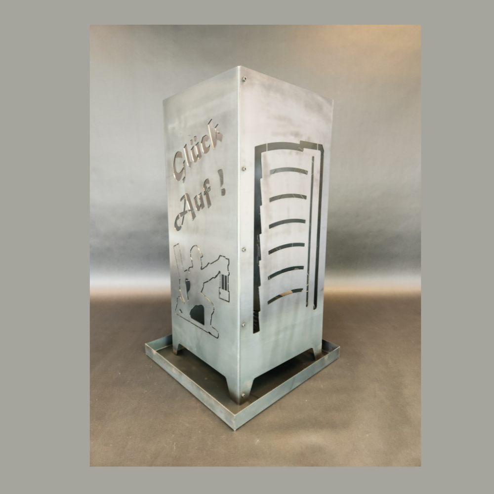 Feuersäule aus Stahl gefertigt in der hauseigenen Produktion. Abmessung 350 x 350 mm und 800 mm hoch. Motiv auf der einen Seite Gasometer, auf der anderen Seite der Schriftzug Glück auf oben und darunter auf der gleichen Seite ein knieender Bergmann.