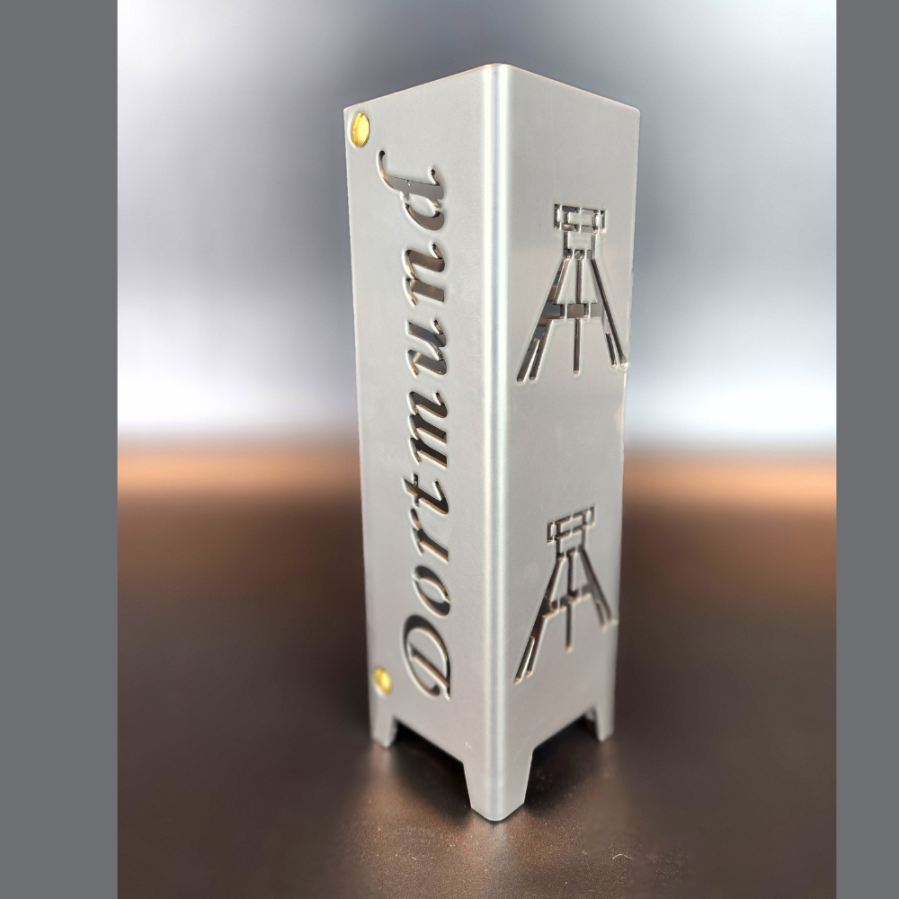 Teelicht aus hochwertigen Stahl gefertigt und in brillant silber pulverbeschichtet. Vierseitig gelasert. Einmal mit dem Schriftzug Dortmund. Dann zweite Seite mit zwei Symbolen Fördertürme. Dritte Seite Schriftzug Ruhrpott und vierte Seite zwei Symbole Ei