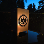 Windlicht aus hochwertigen Metall gefertigt. Der Adler, das Logo von Eintracht Frankfurt ist vollständig zu sehen und auch zwei Seiten, gegenüberliegend. Die Abmessung ist 120 mm mal 120 mm und 200 mm hoch.