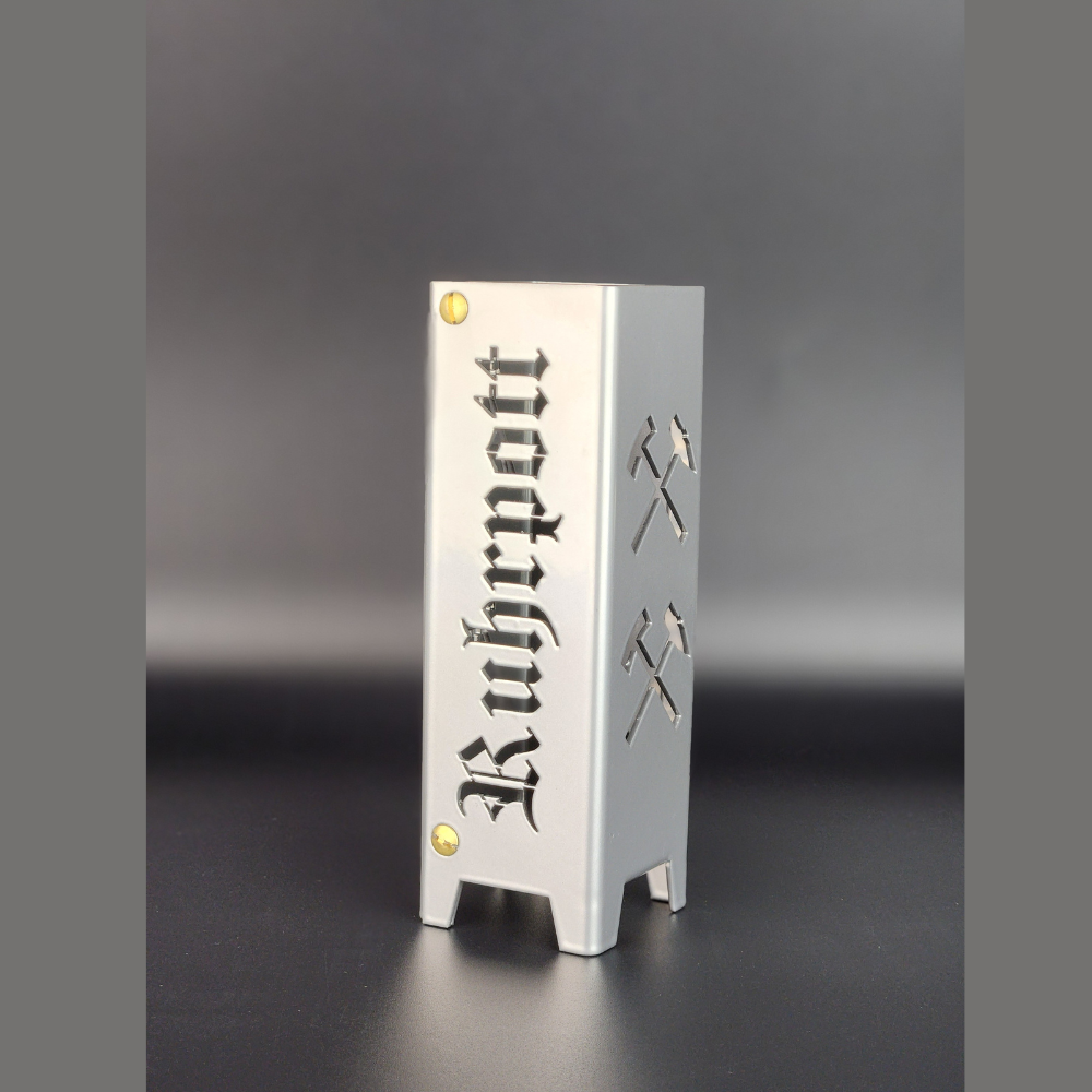 Teelicht aus hochwertigen Metall gefertigt und in brillant silber pulverbeschichtet. Schriftzug Ruhrpott und auf der anderen Seite Symbole Eisen und Schägel, jeweils zwei Symbole übereinander. Für den Innenbereich geeignet.