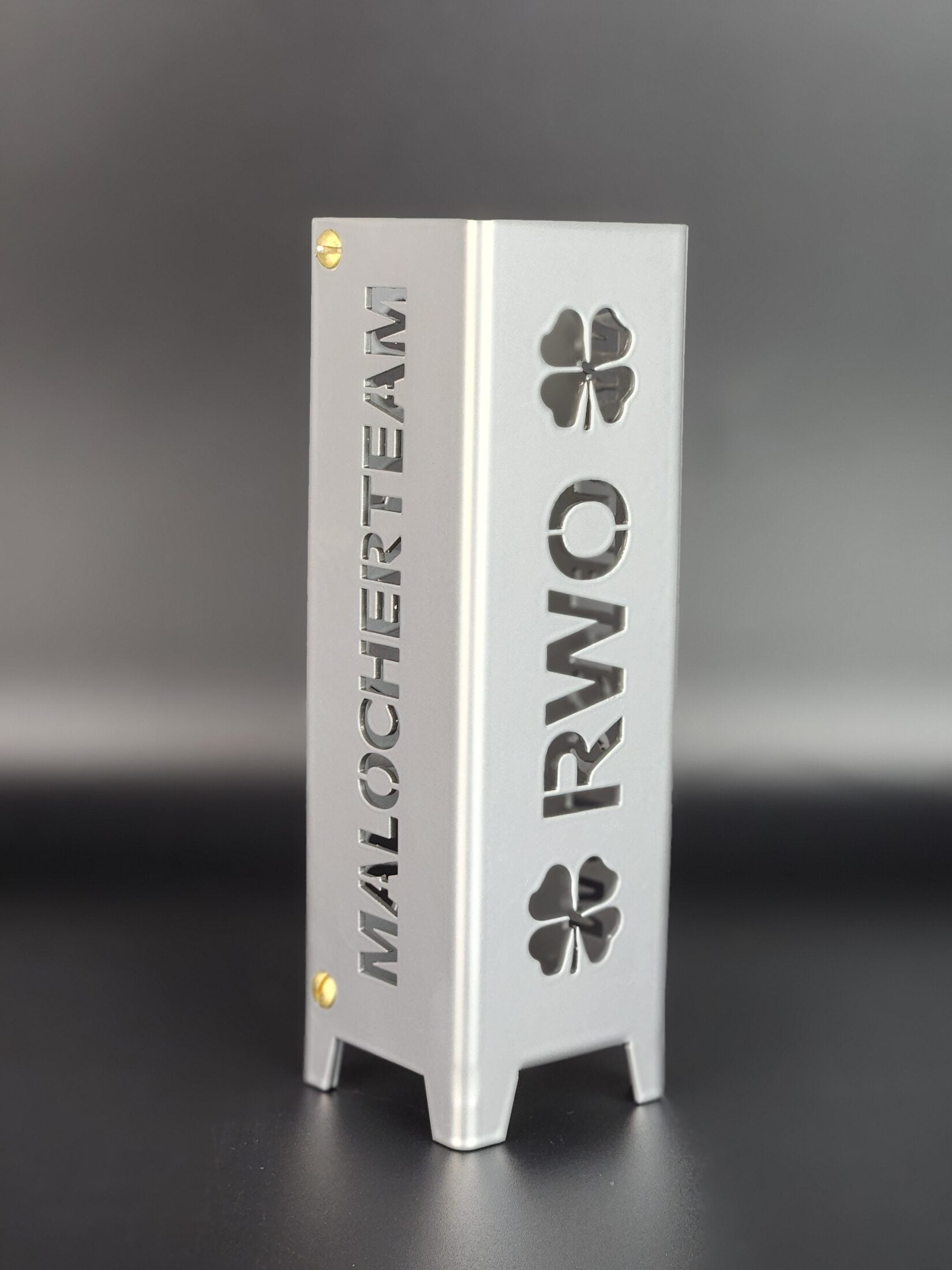 Teelicht aus Metall mit dem Buchstaben großgeschrieben RWO und einem Kleeblatt am Anfang und Ende von RWO. Malocherteam als Schriftzug auf jeweils zwei gegenüberliegenden Seiten. Das Teelicht RWO ist aus hochwertigen Stahl gefertigt und in Brillant silber